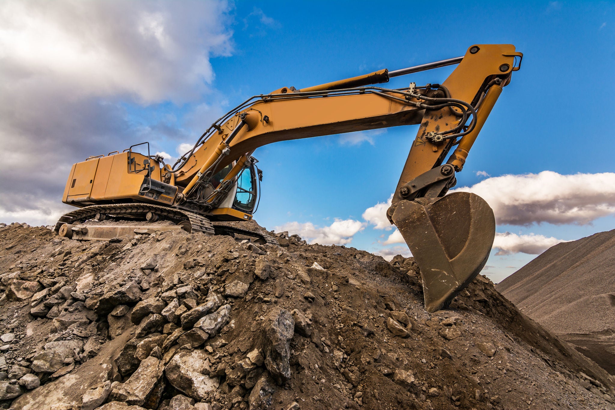 IN_QM_Excavator_Shutterstock_1444855289.jpg QM Industry, Excavator performing stone extraction work in an open pit stone mine